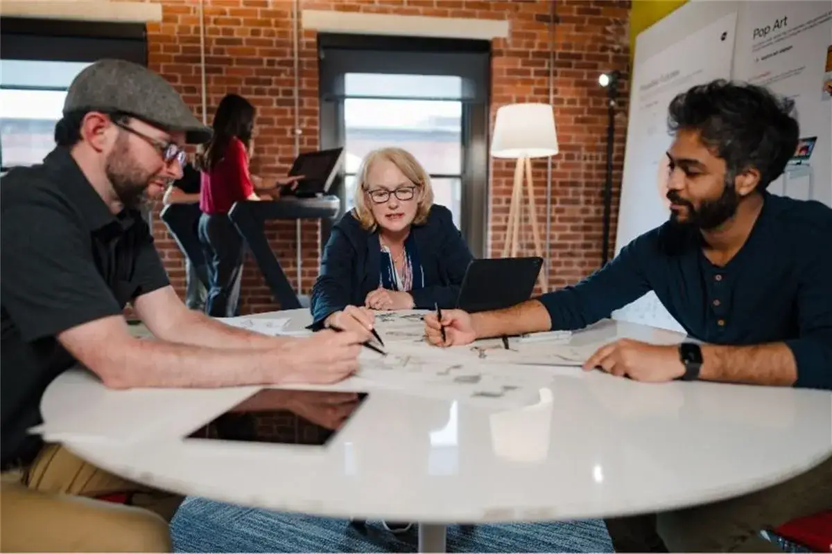A diverse team collaborates around a table, sketching ideas. They are a change agent group, focused on innovation and future projects.