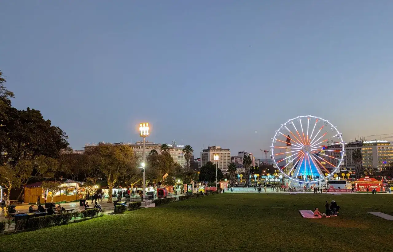 Ein beleuchtetes Riesenrad und Buden schaffen eine magische Atmosphäre im Wonderland Lisboa.