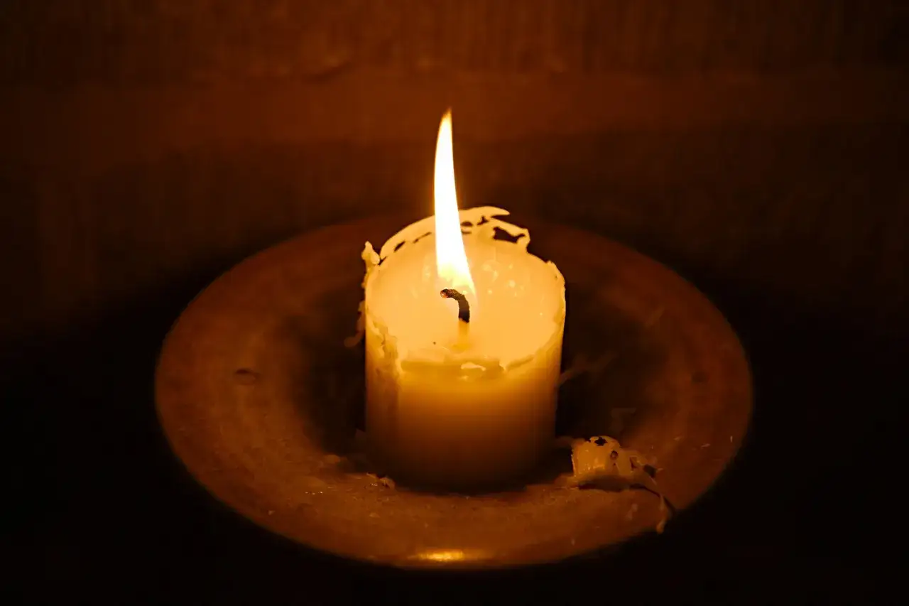 Eine brennende Kerze auf einem Teller, ihr Licht erinnert an Psalm 139,14: 