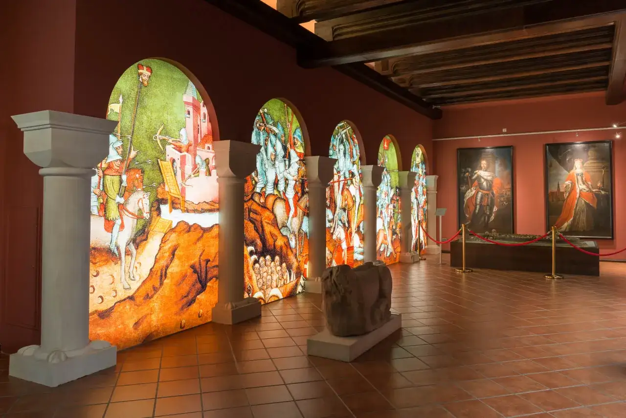 Wystawa w jednym z muzeów we Wrocławiu: podświetlane arkady z historycznymi scenami bitewnymi i portrety władców.