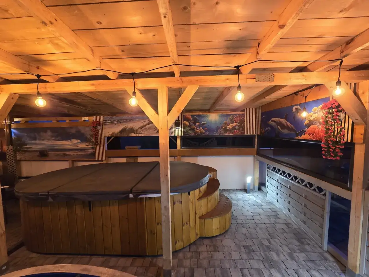Relaks w domkach Posejdon Jastrzębia Góra. Drewniana wanna z hydromasażem pod zadaszeniem, ozdobionym morskimi muralami.