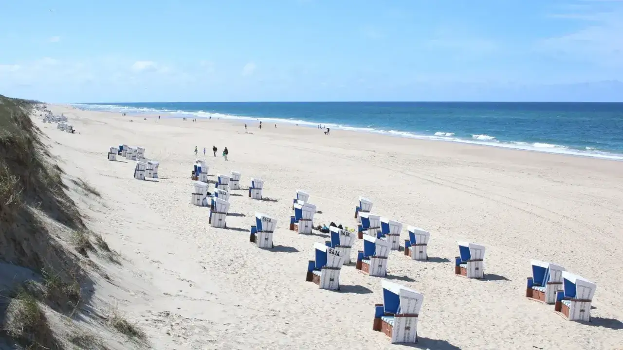 Ein sonniger Tag am Meer, perfekt für eine Reise von Hamburg ans Meer mit der Bahn. Strandkörbe warten auf Besucher.