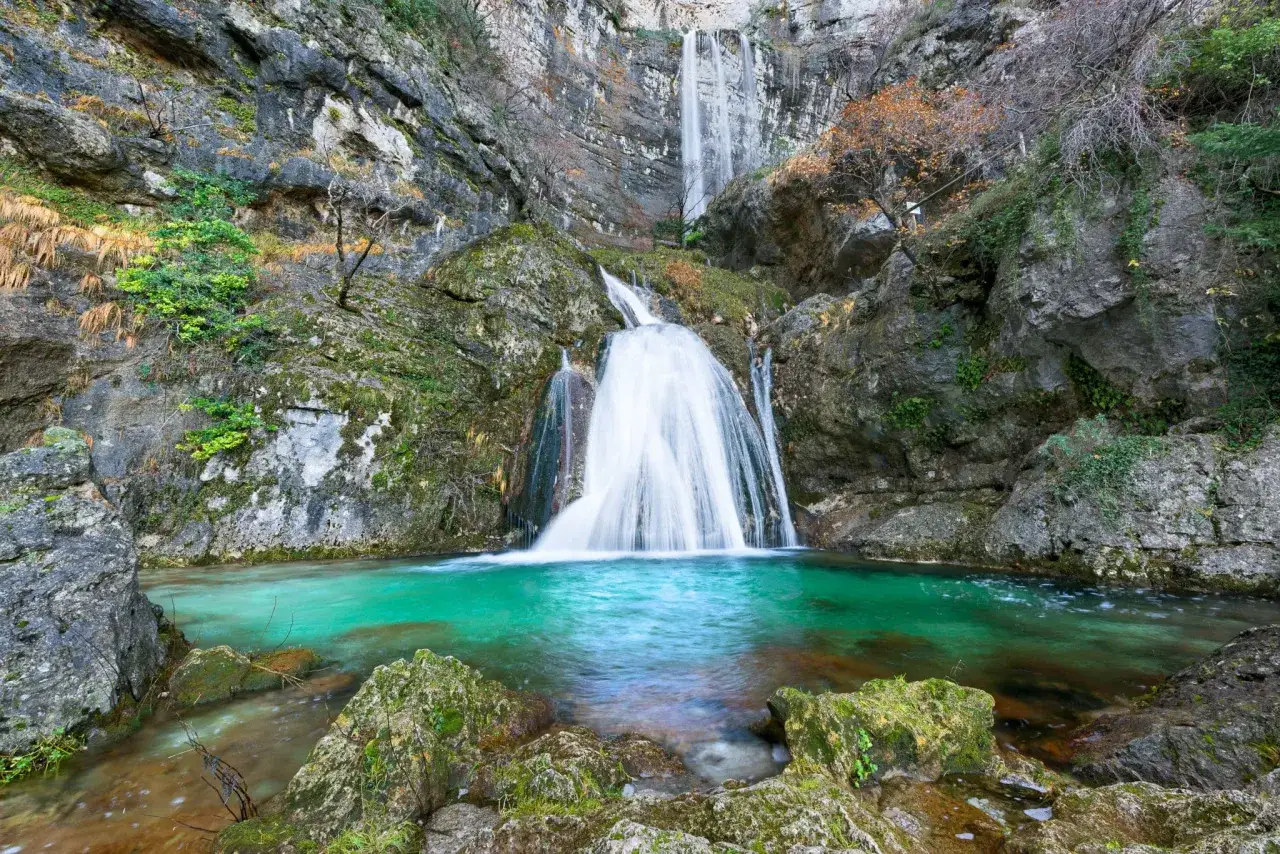 Cascada espectacular en el lagunazo riopar, con aguas turquesas y rocas cubiertas de musgo.