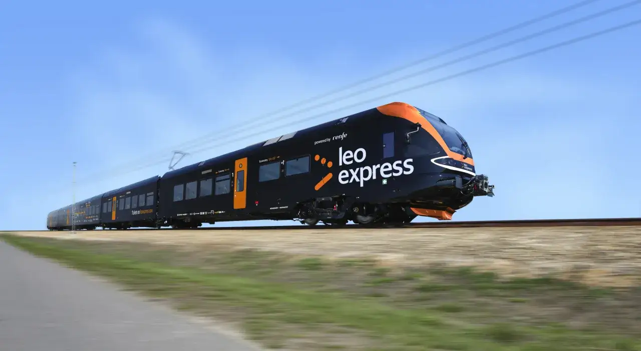 Czarny pociąg Leo Express z pomarańczowymi akcentami mknie po torach. To Twój pociąg do Pragi z Krakowa, gotowy na podróż!