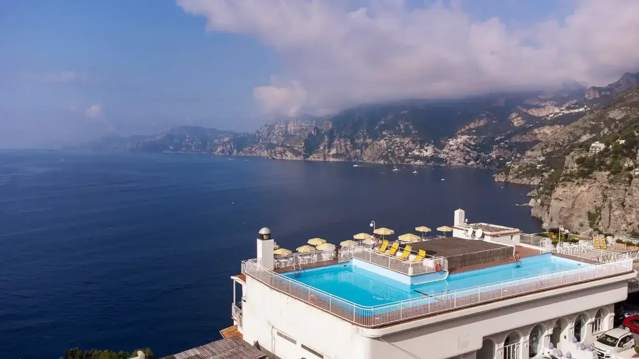 Piscina panoramica con vista mare mozzafiato, lettini e ombrelloni gialli. Il **hotel tramonto d'oro** offre un sogno di vacanza sulla costa.