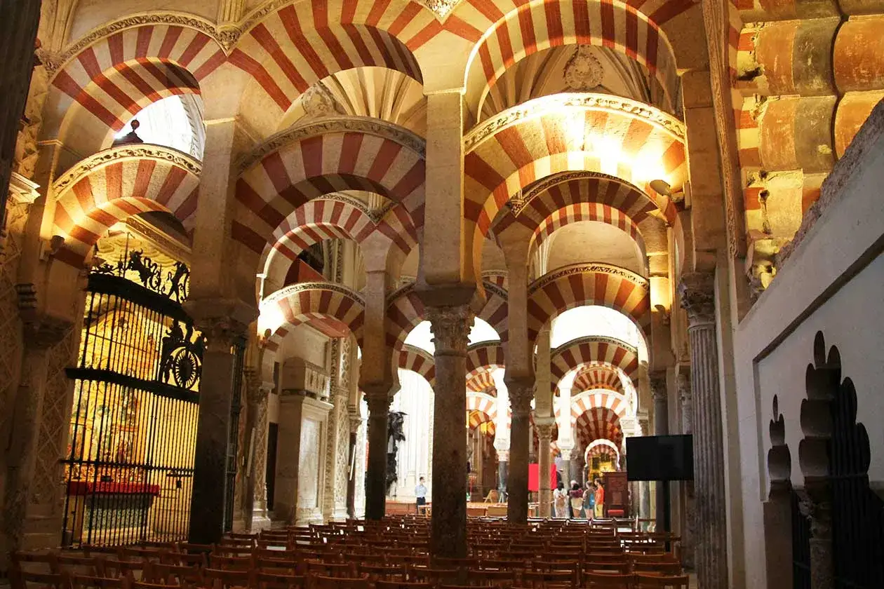 Interior de la mezquita de C&oacute;rdoba, con sus ic&oacute;nicos arcos bicolores y columnas que crean un laberinto arquitect&oacute;nico.