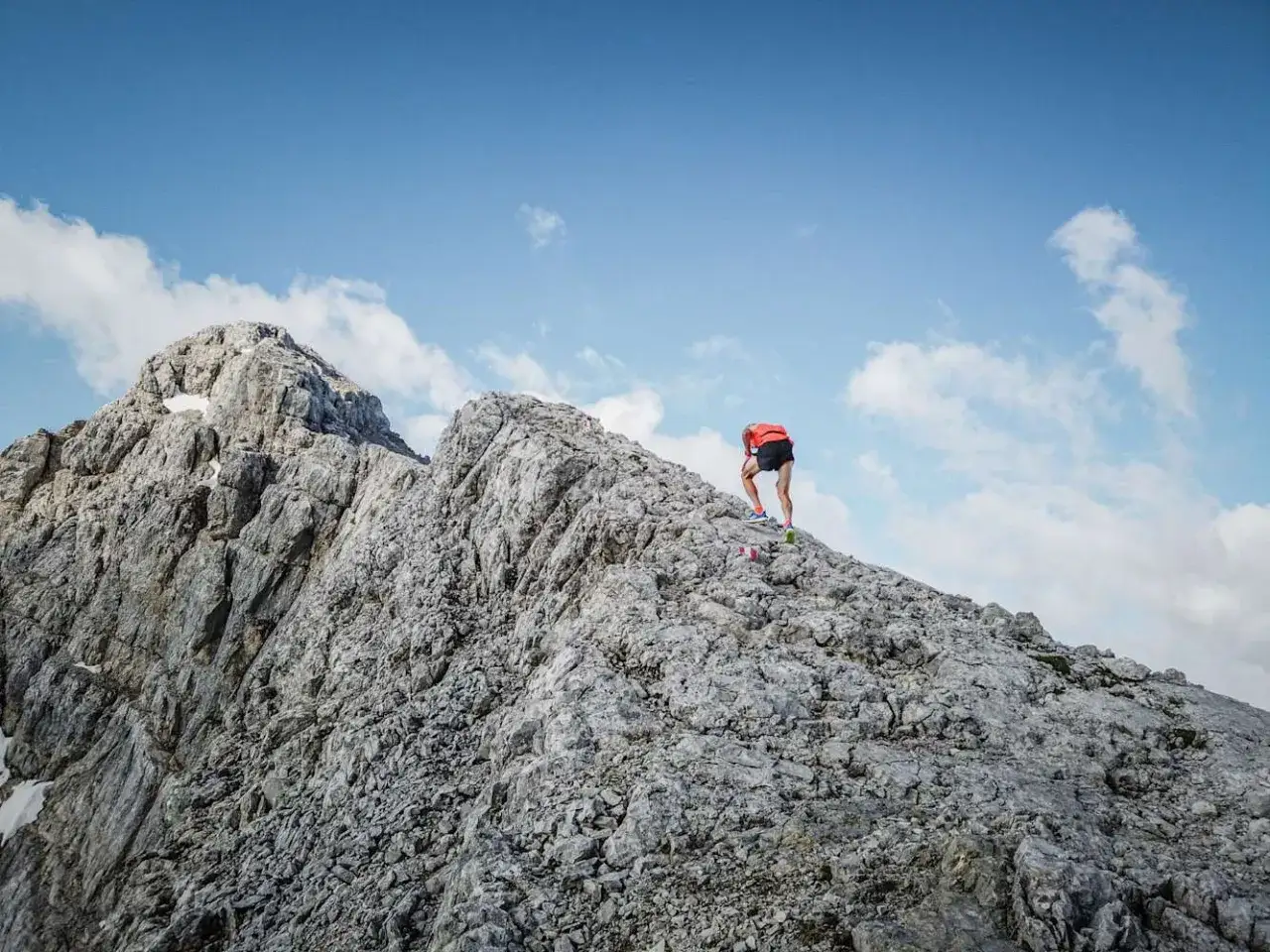 Anton Palzer erklimmt den Watzmann. Der Bergsteiger in rotem Shirt und schwarzer Hose k&auml;mpft sich &uuml;ber steiniges Gel&auml;nde.