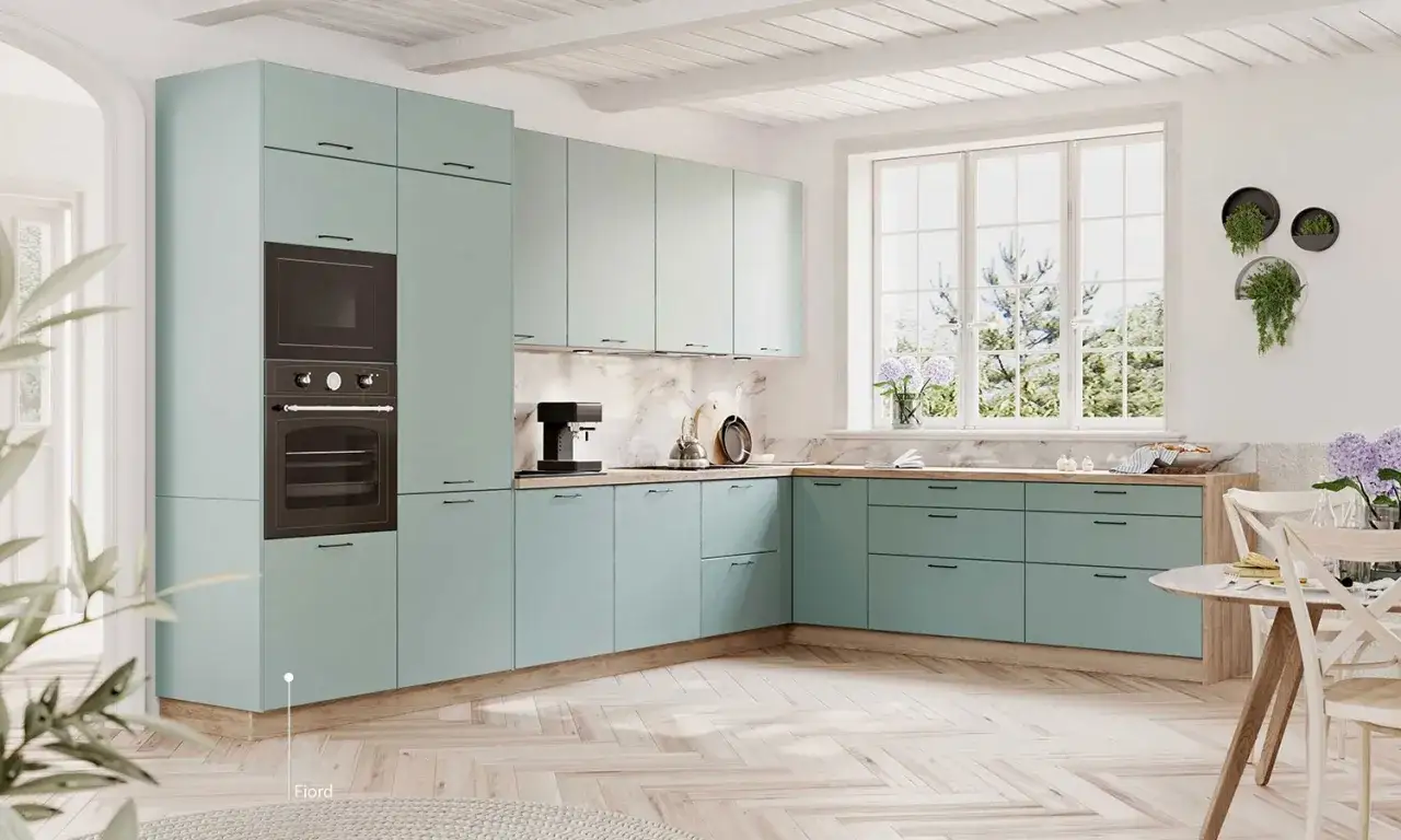Jasna kuchnia w stylu shabby chic z miętowymi frontami, drewnianym blatem i dużym oknem.