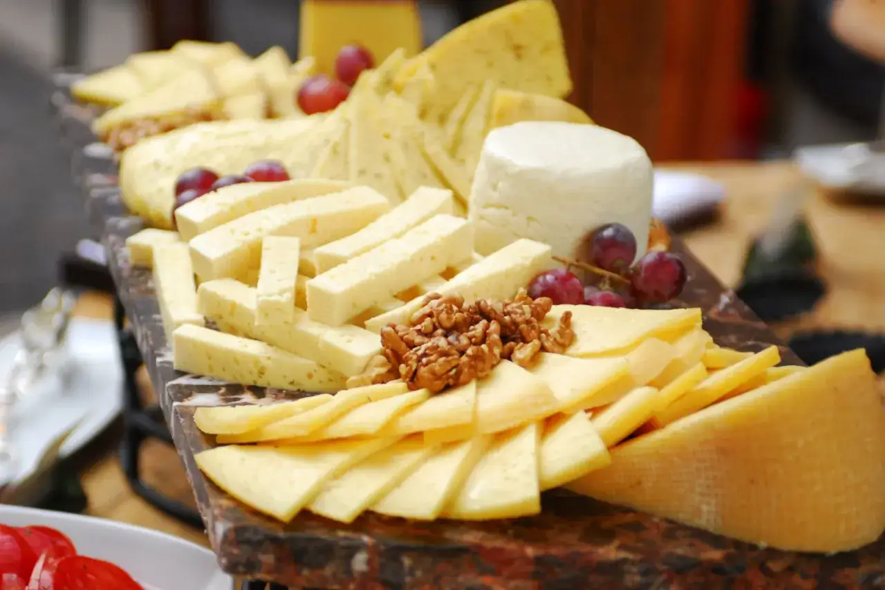Tabla de quesos variados, cortados en diferentes formas, ideal para aprender como cortar queso y disfrutar de un aperitivo.