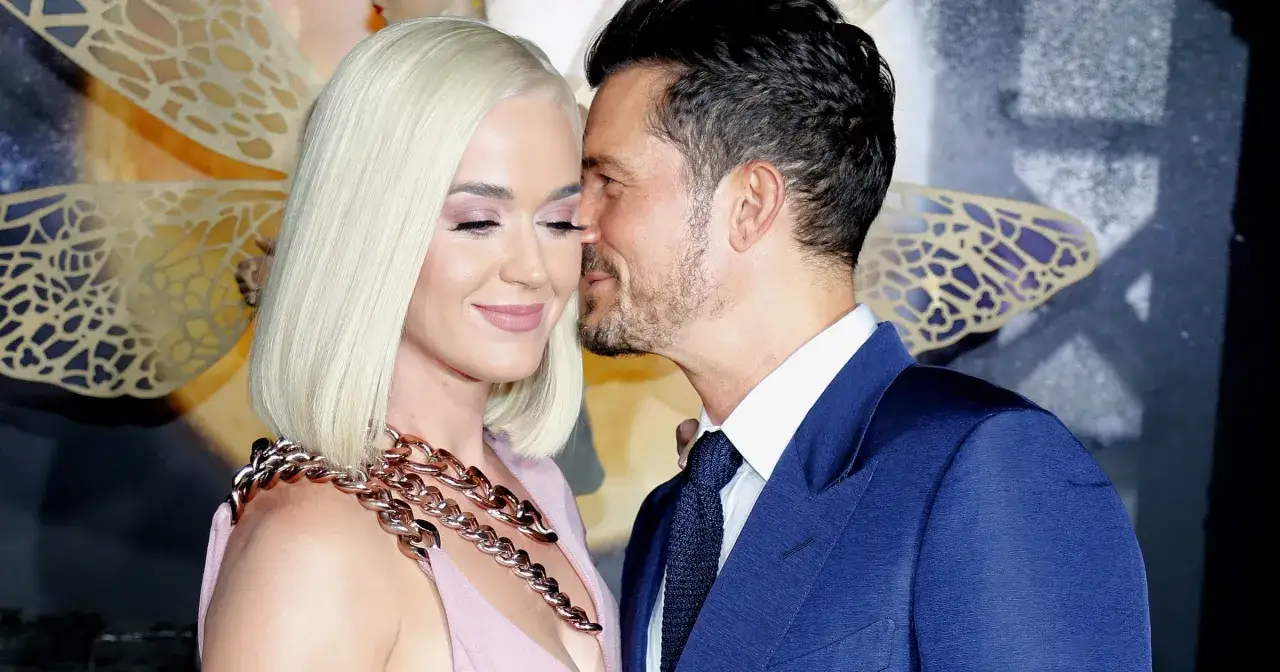 Katy Perry i Orlando Bloom w czułym uścisku. Ona w różowej sukni z grubym naszyjnikiem, on w granatowym garniturze.