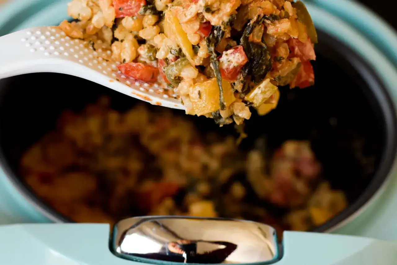 Ein L&ouml;ffel hebt eine Portion k&ouml;stlichen Bulgurs mit Gem&uuml;se aus einem Topf. Das Bulgur kochen ist eine gesunde und einfache Zubereitung.