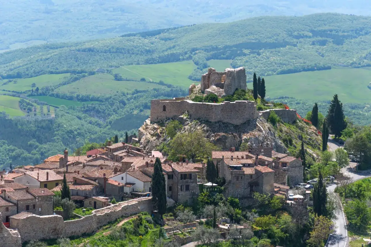 Castiglione d'Orcia: cosa vedere? Un borgo medievale con un castello arroccato su una collina, circondato da dolci colline toscane.