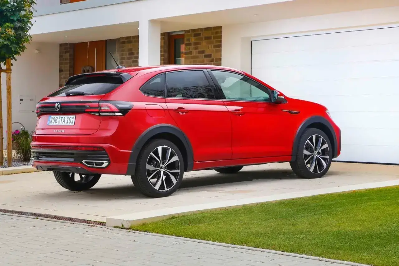 Czerwony VW Taigo zaparkowany przed nowoczesnym domem. Poznaj jego wymiary i możliwości.