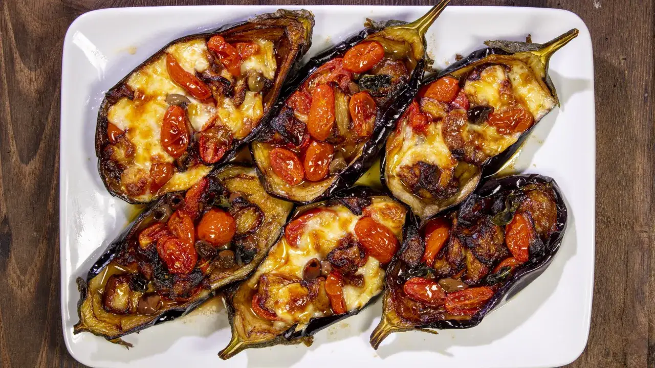 Melanzane a scarpone ripiene di pomodorini e formaggio fuso, cotte al forno fino a doratura. Un piatto invitante e saporito.