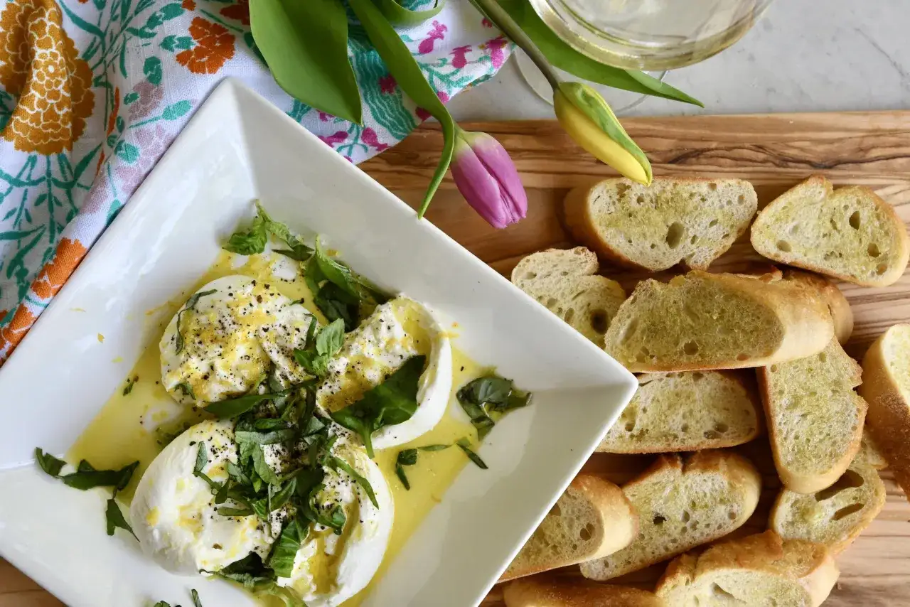 Cremige Burrata mit Basilikum und Zitrone, serviert mit geröstetem Brot. Ein Genuss für jeden Gaumen.