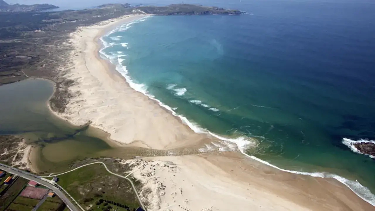Vista a&eacute;rea de la playa a lanzada, con dunas, laguna y el mar azul.