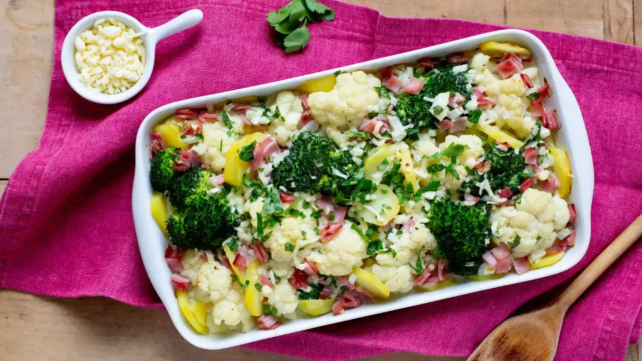 Herzhafter blumenkohl brokkoli auflauf mit Schinken und K&auml;se, garniert mit Petersilie.
