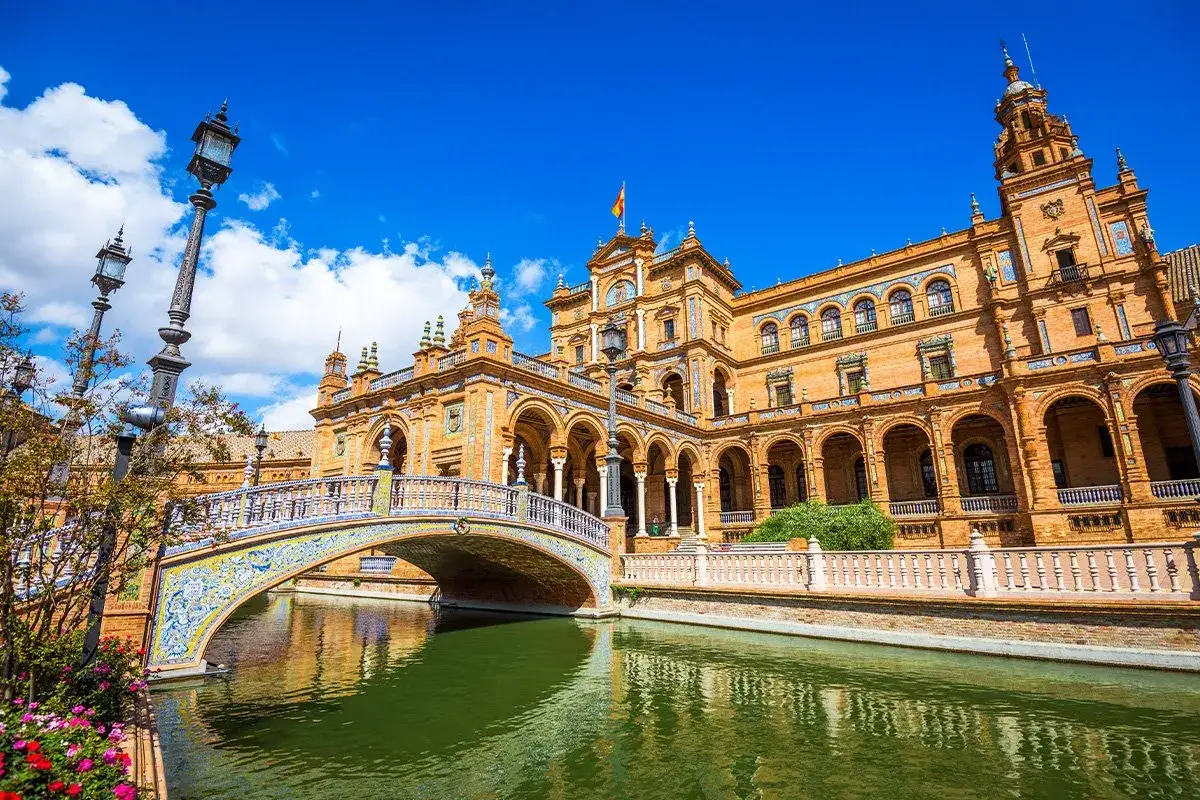 Mostek zdobiący Plaza de España w Sewilli, piękne miasto Andaluzji, odbija się w zielonej wodzie kanału.