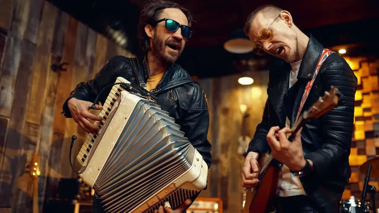 Zwei Musiker mit Lederjacken und Sonnenbrillen spielen Akkordeon und Gitarre. Sie sind Teil der Musikindustrie und rocken die Bühne.