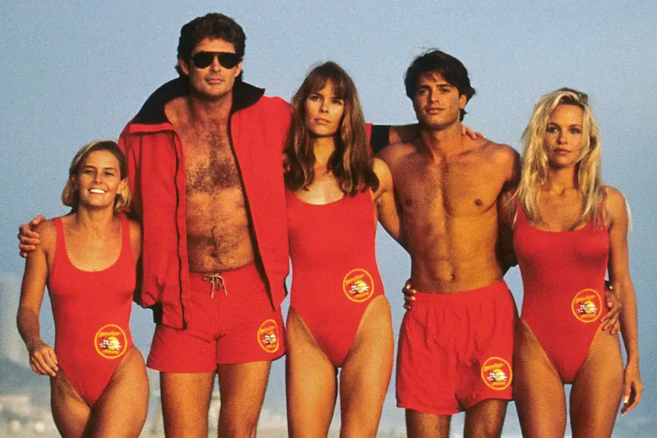 Słynna obsada Baywatch Słoneczny Patrol w czerwonych strojach ratowniczych na plaży.