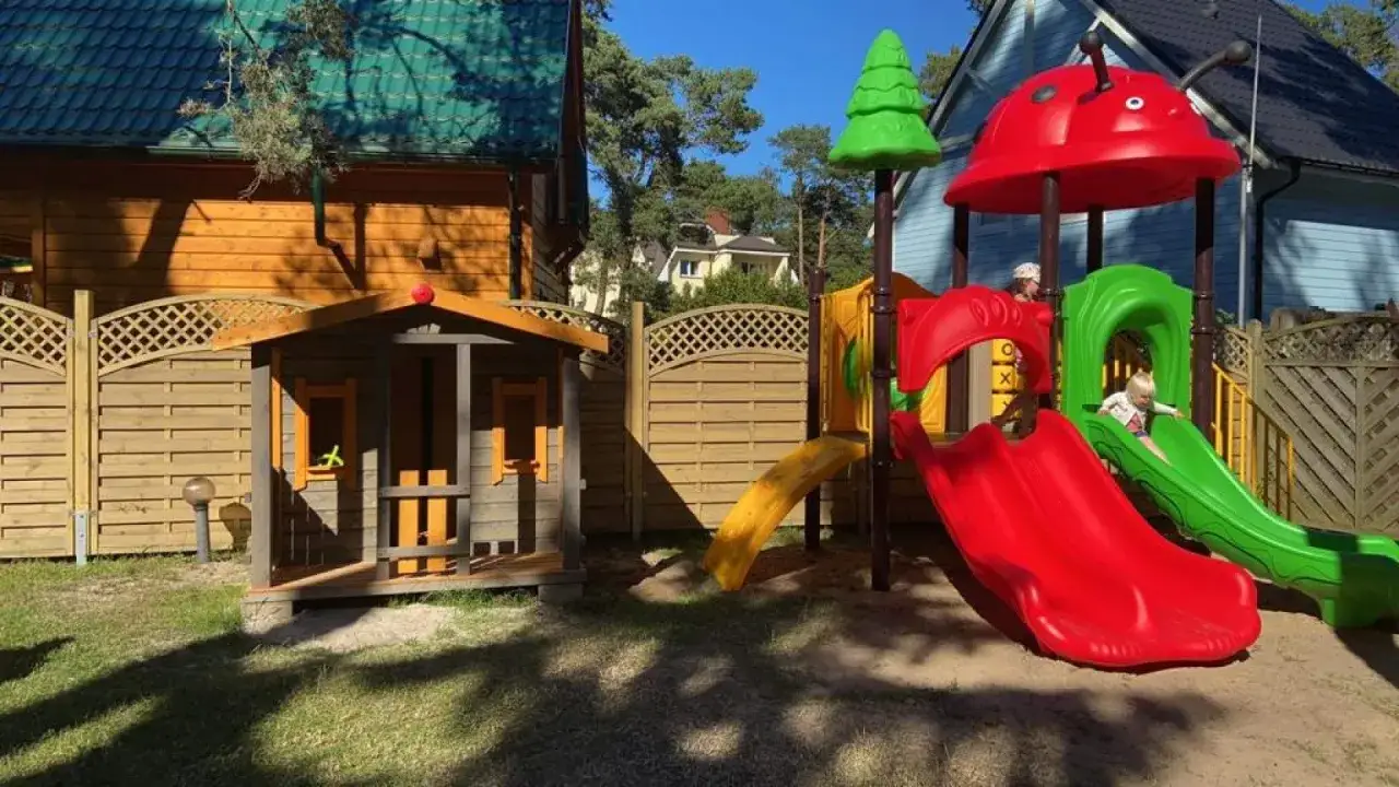 Kolorowy plac zabaw z domkami letniskowymi w nawarapark pobierowo. Dzieci bawią się na zjeżdżalniach.