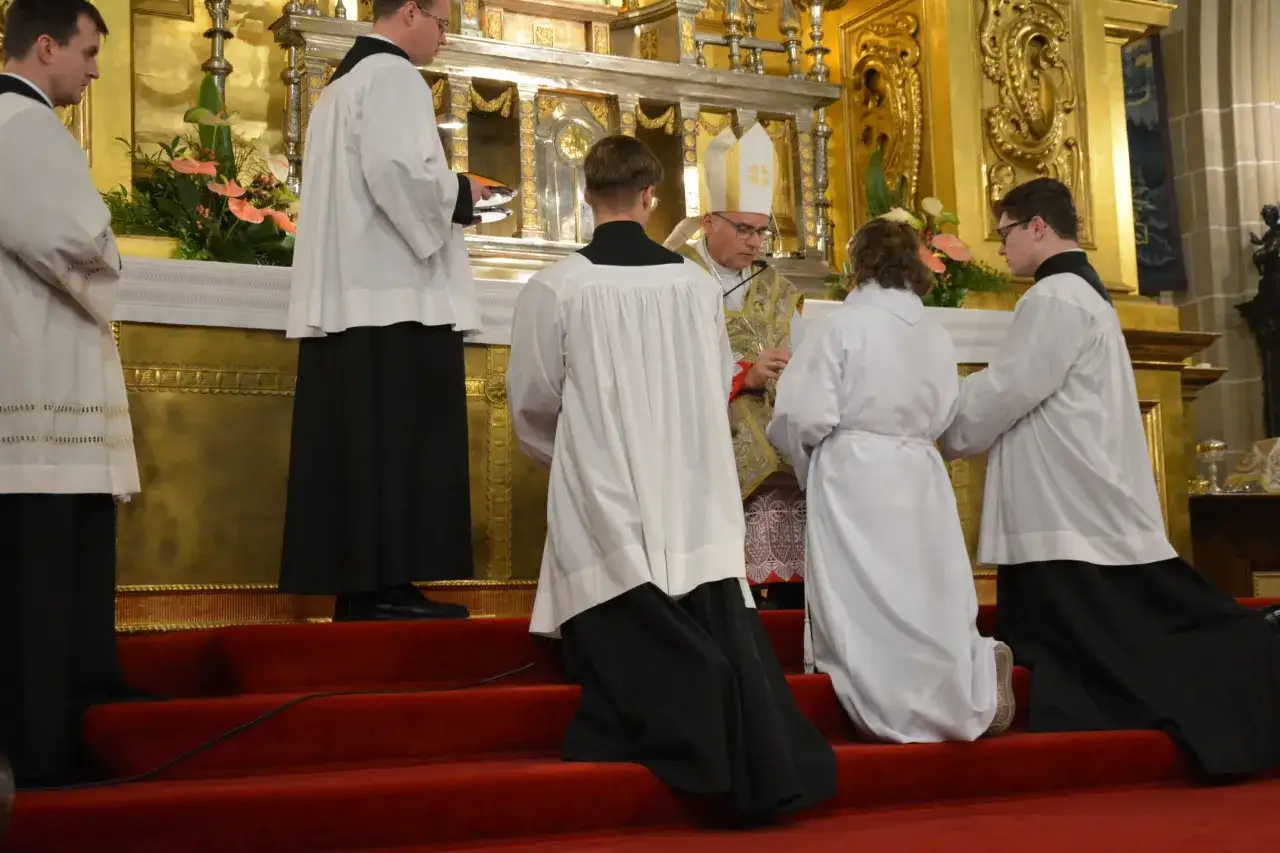 Biskup udziela błogosławieństwa dziewicy konsekrowanej podczas uroczystej mszy w kościele.