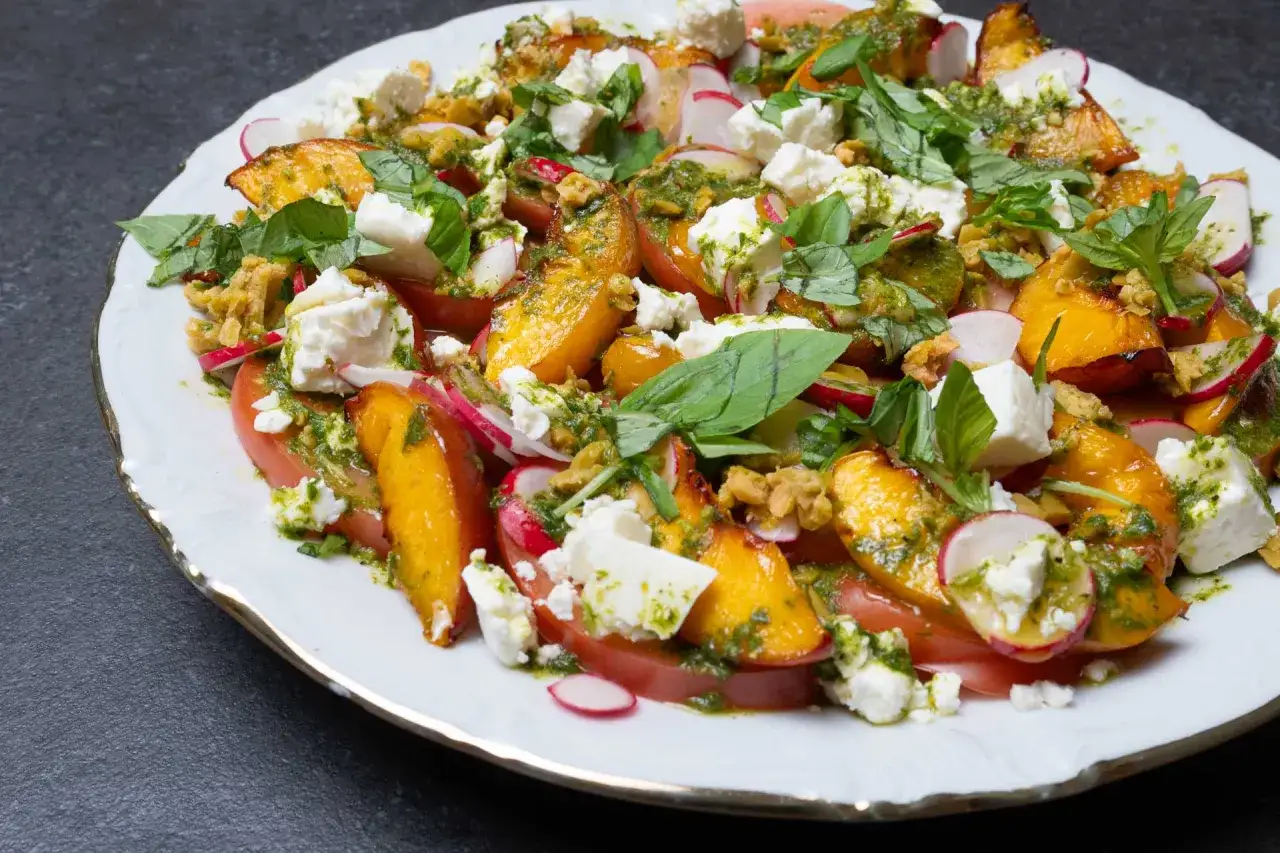 Ein bunter Salat mit Nektarinen, Tomaten, Radieschen, Feta und Kr&auml;utern, betr&auml;ufelt mit einem gr&uuml;nen Dressing.