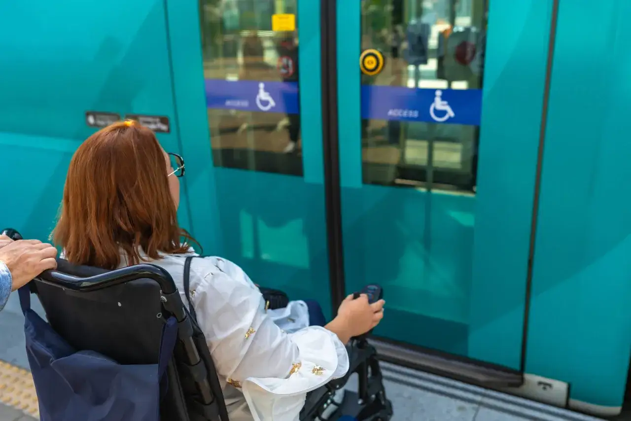Kobieta na wózku elektrycznym czeka na dostęp do pojazdu. Znaczny stopień niepełnosprawności przywileje to dostępność.
