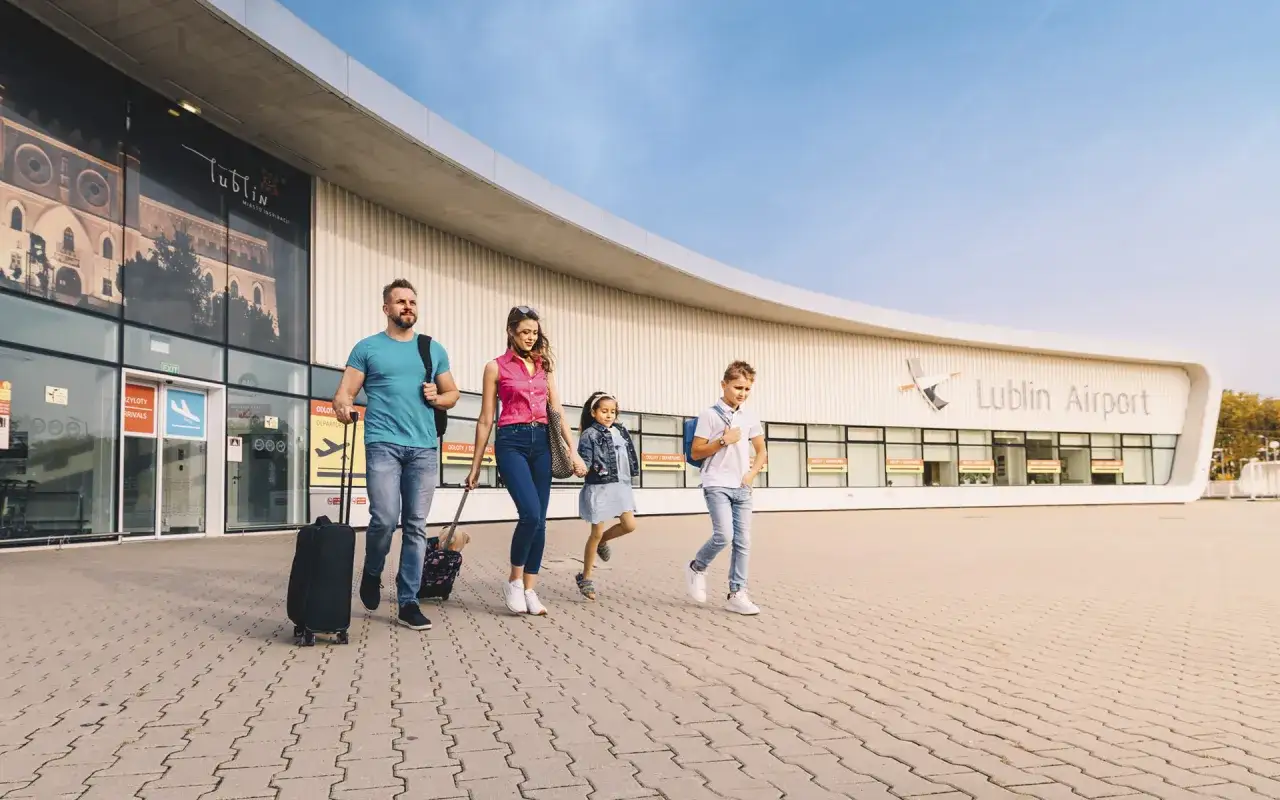 Rodzina z walizkami idzie na lotnisko Lublin odloty.