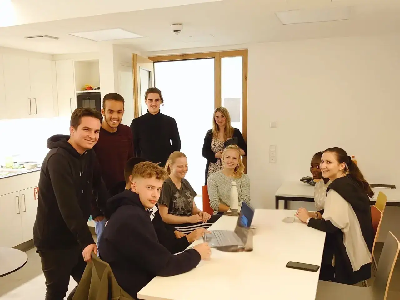 Eine Gruppe junger Leute im Sophie Barat Haus, die sich um einen Tisch versammelt haben.