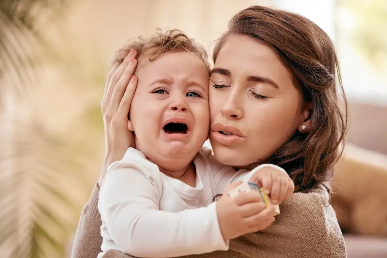 Roczne dziecko ciągle płacze i chce na ręce. Mama tuli je, próbując uspokoić.