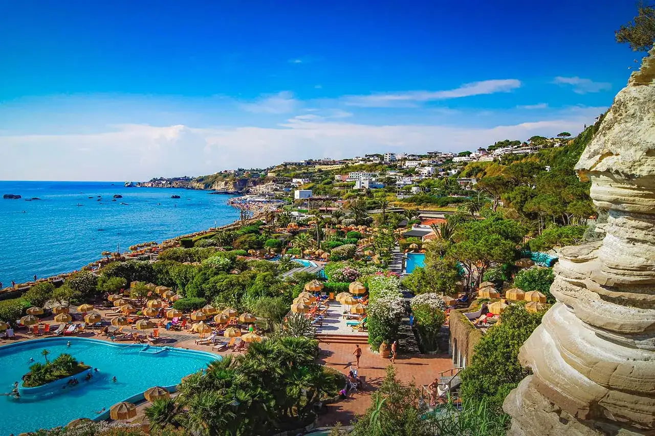 Vista panoramica di un lussureggiante resort con piscine e spiaggia, un vero paradiso per il tuo benessere a spa Ischia.