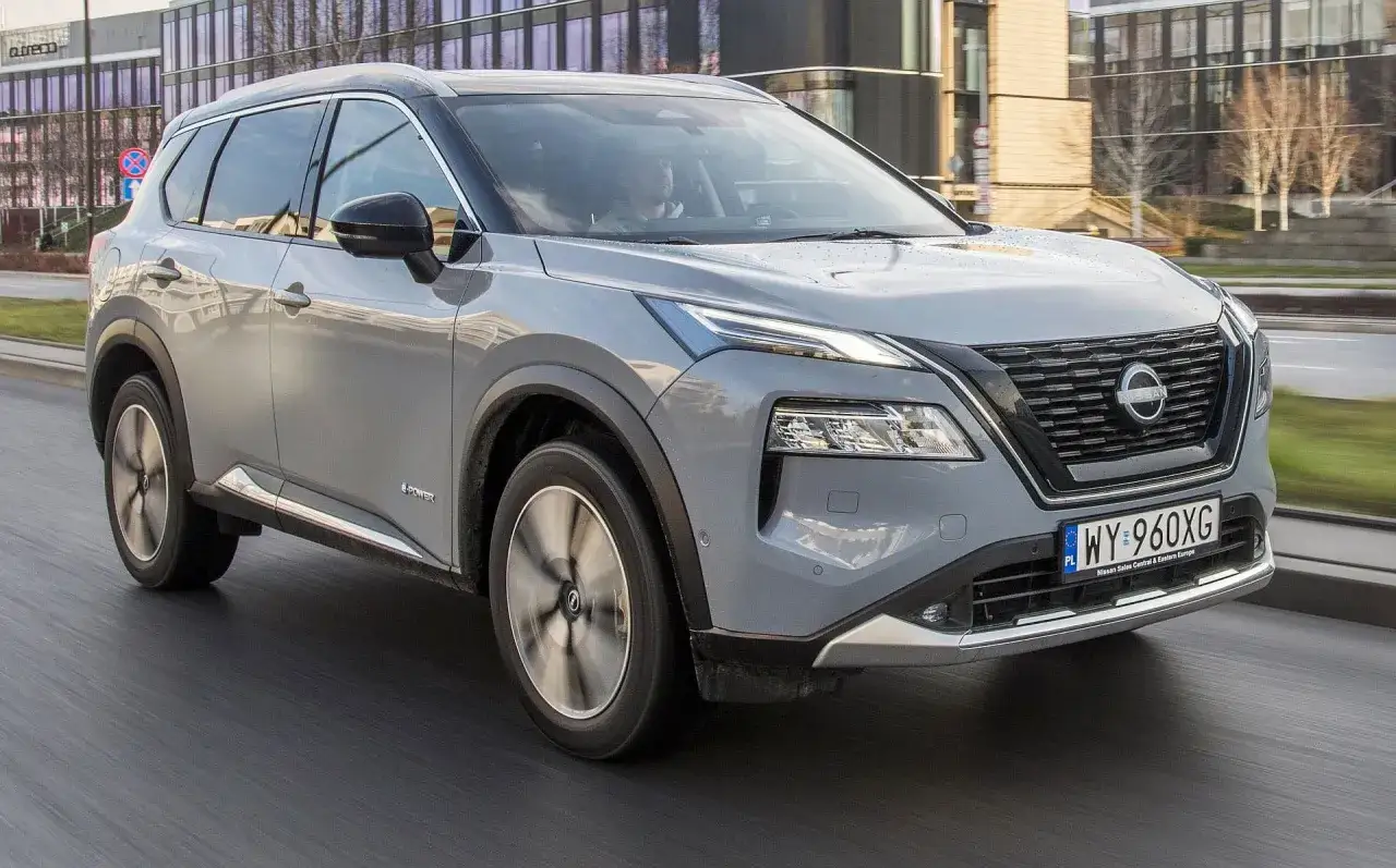 Szary Nissan X-Trail e-POWER w ruchu miejskim. Kierowca testuje jego niskie spalanie.