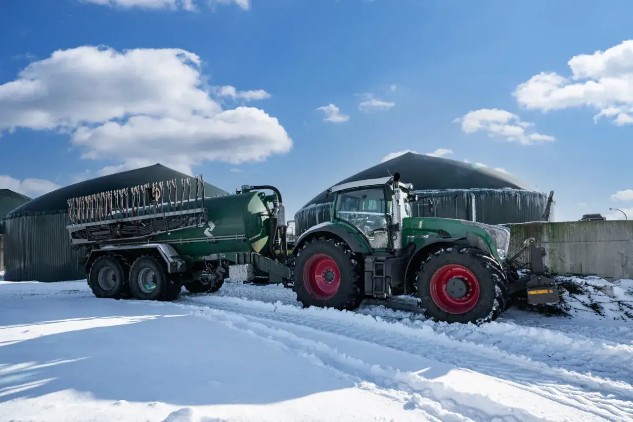 Traktor mit Güllefass im Schnee vor Biogasanlagen. Der **Kalkstickstoff Verbot** könnte Auswirkungen auf solche Anlagen haben.