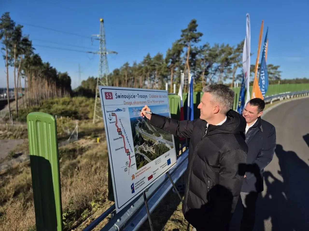 Mężczyzna wskazuje na mapę drogi S3, która pokazuje trasę Świnoujście-Troszyn. Dowiadujemy się, ile jest kilometrów ze Szczecina do Świnoujścia.