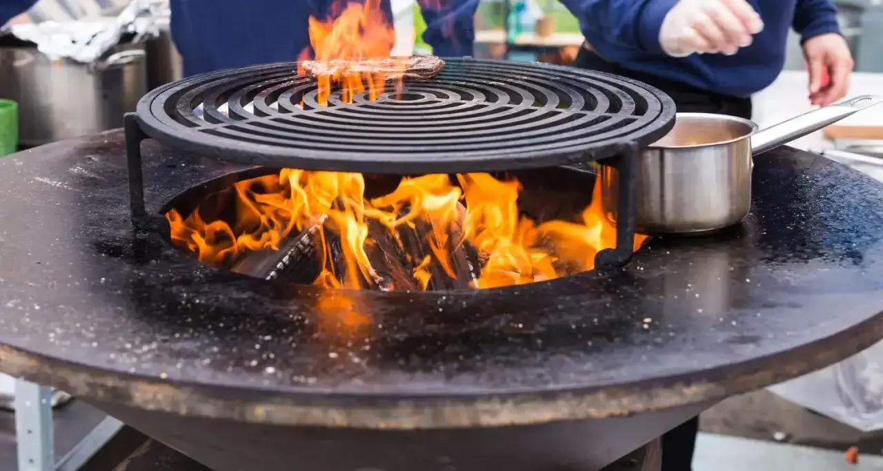 Un brasero en feu avec un steak sur la grille. Pensez à comment nettoyer un brasero après usage pour qu'il reste beau.