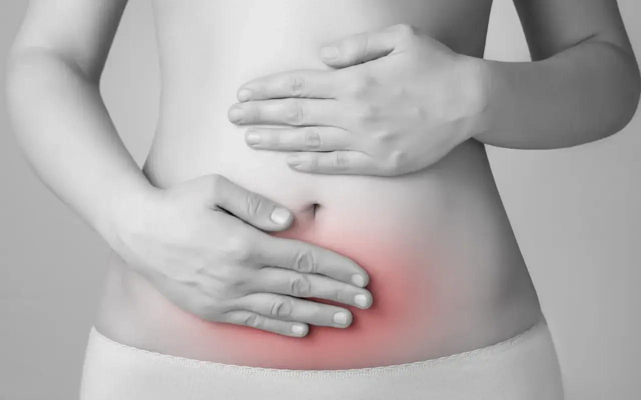 Mani sul ventre, evidenziando un'area rossa di dolore. L'endometriosi pu&ograve; causare invalidit&agrave; e limitare la vita quotidiana.