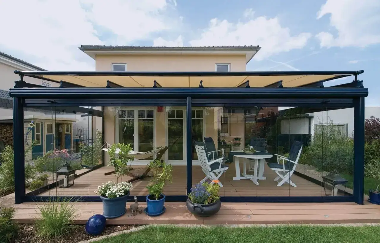 Terraza moderna con **fachada de cristal** y muebles de exterior. Un toldo retráctil protege del sol.