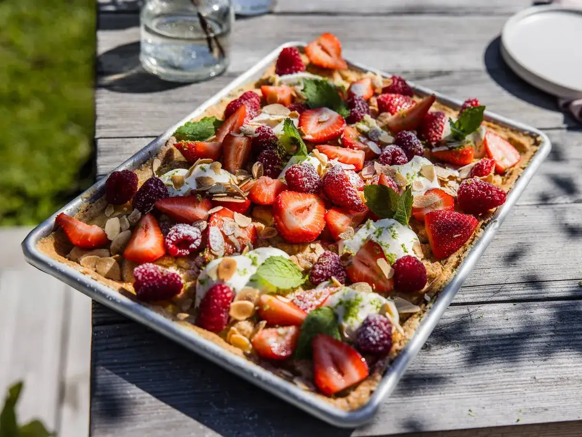 Enkel t&aring;rta till m&aring;nga, t&auml;ckt med f&auml;rska jordgubbar, hallon, gr&auml;dde och mandel. Perfekt f&ouml;r sommarens firanden.