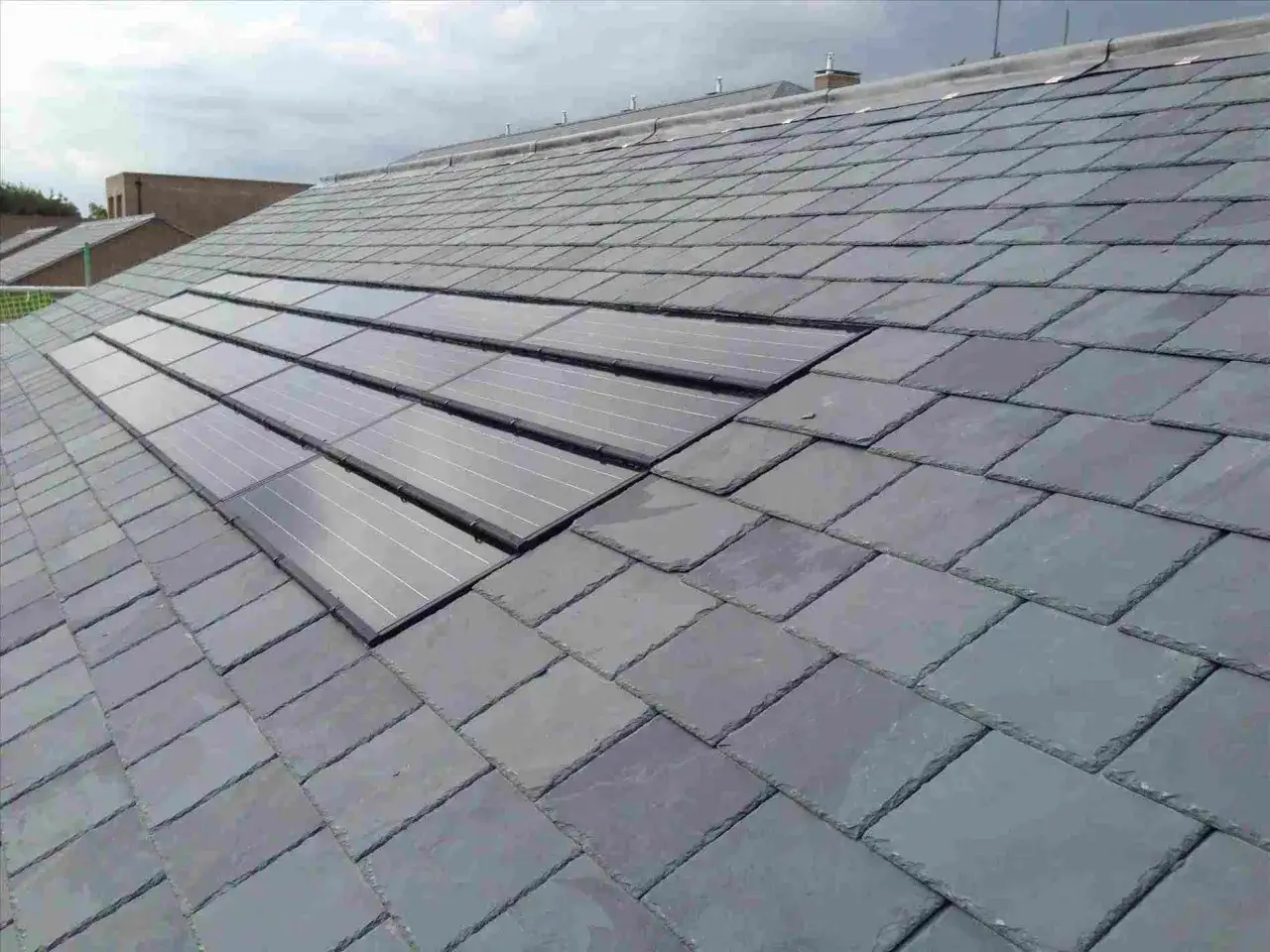 Panneaux solaires intégrés dans une toiture en ardoise, pour un chauffage solaire discret et esthétique.