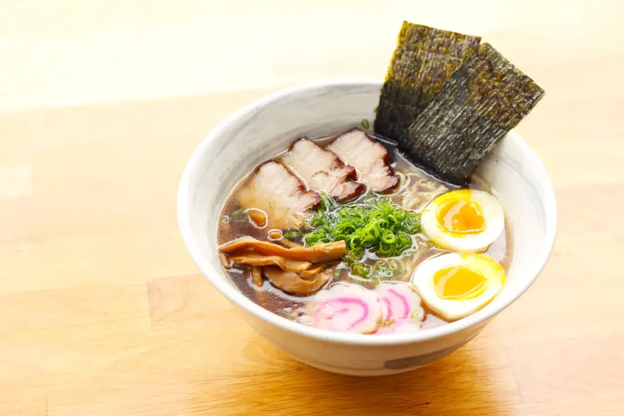 A miseczce shoyu ramen z plastrami wieprzowiny, jajkiem na pół, nori i zieloną cebulką.