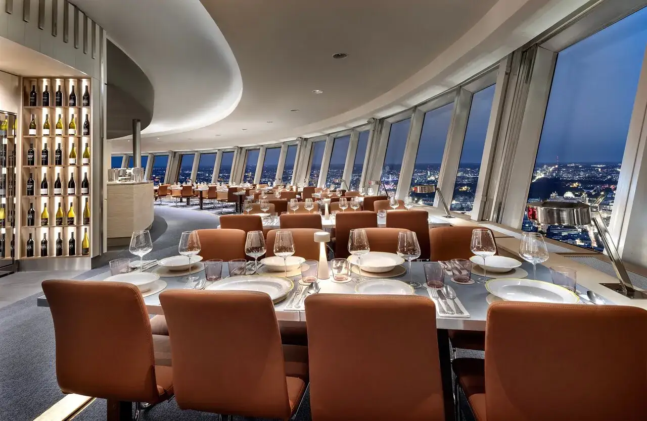 Elegant restaurang med utsikt &ouml;ver staden, perfekt f&ouml;r att uppleva bra restauranger i Berlin. Vinhyllor och bord med dukning.