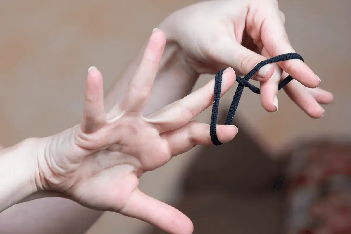 Dłonie tworzą pętlę z czarnej gumki, przygotowując się do szycia scrunchie.