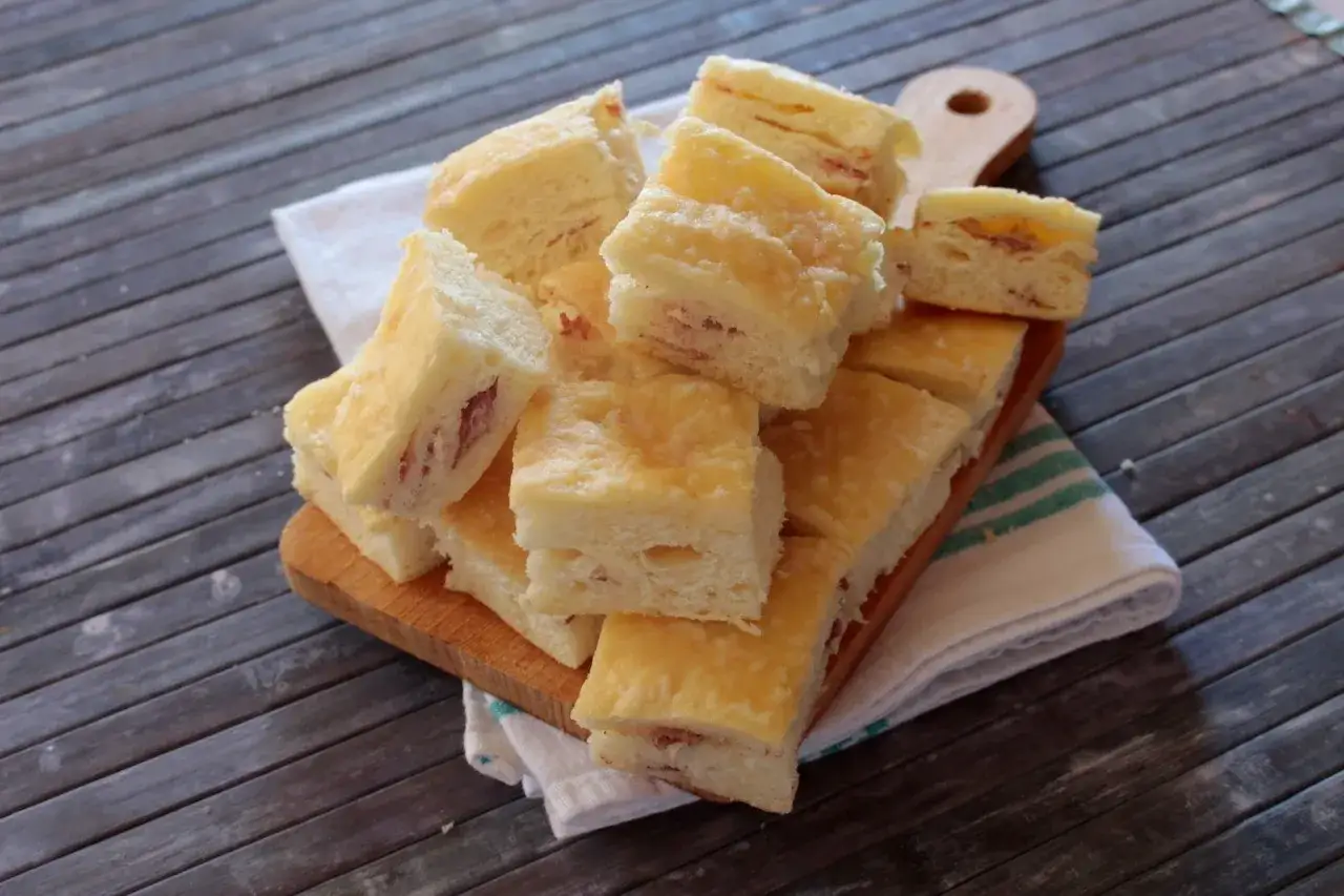 Pila di gnocco fritto al forno, tagliato a cubetti, con prosciutto visibile all'interno.
