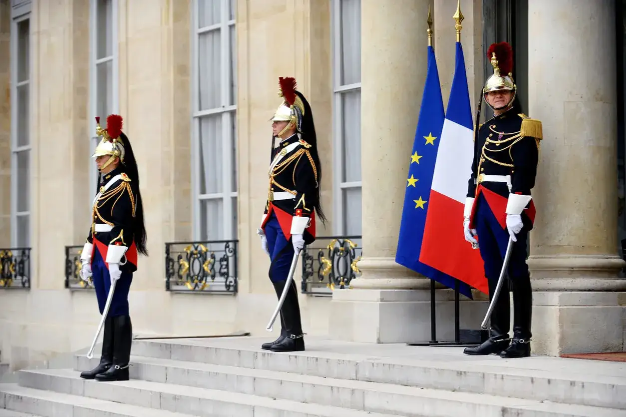 Garde républicaine en tenue d'apparat, devant des drapeaux français et européen. Un homme est persona non grata.