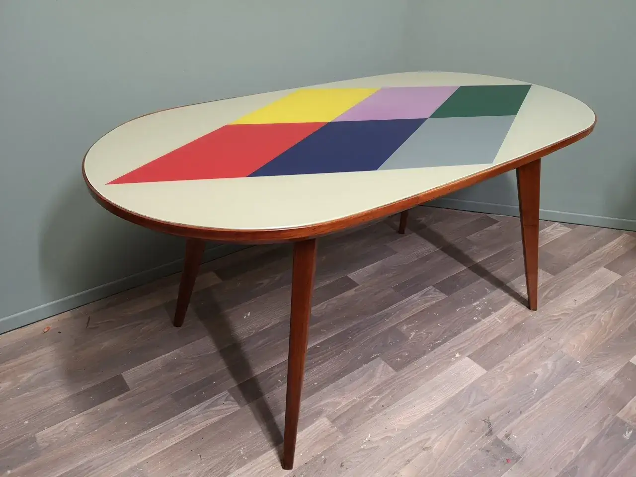 Tavolino anni '70 con piano ovale decorato a rombi colorati. Un esempio di come rinnovare mobili vintage con stile.