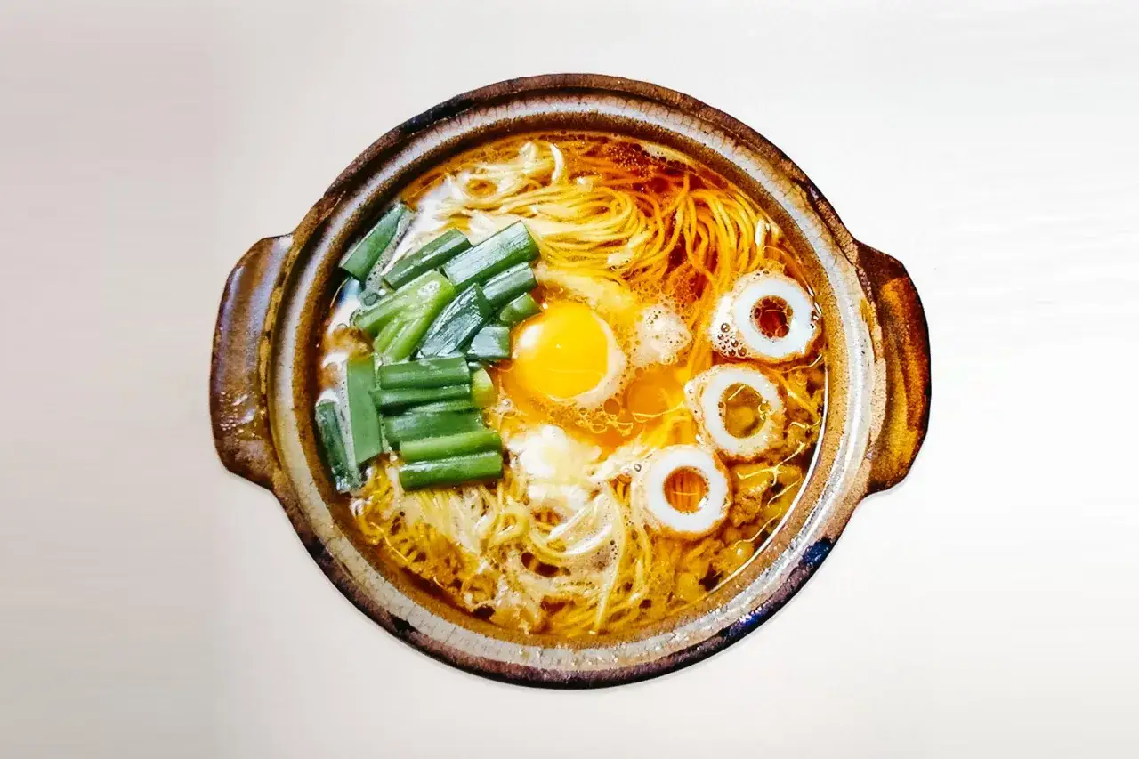 Aksamitny bulion, cienki makaron do ramen, jajko sadzone, zielona cebulka i rybne kółka tworzą apetyczną kompozycję.