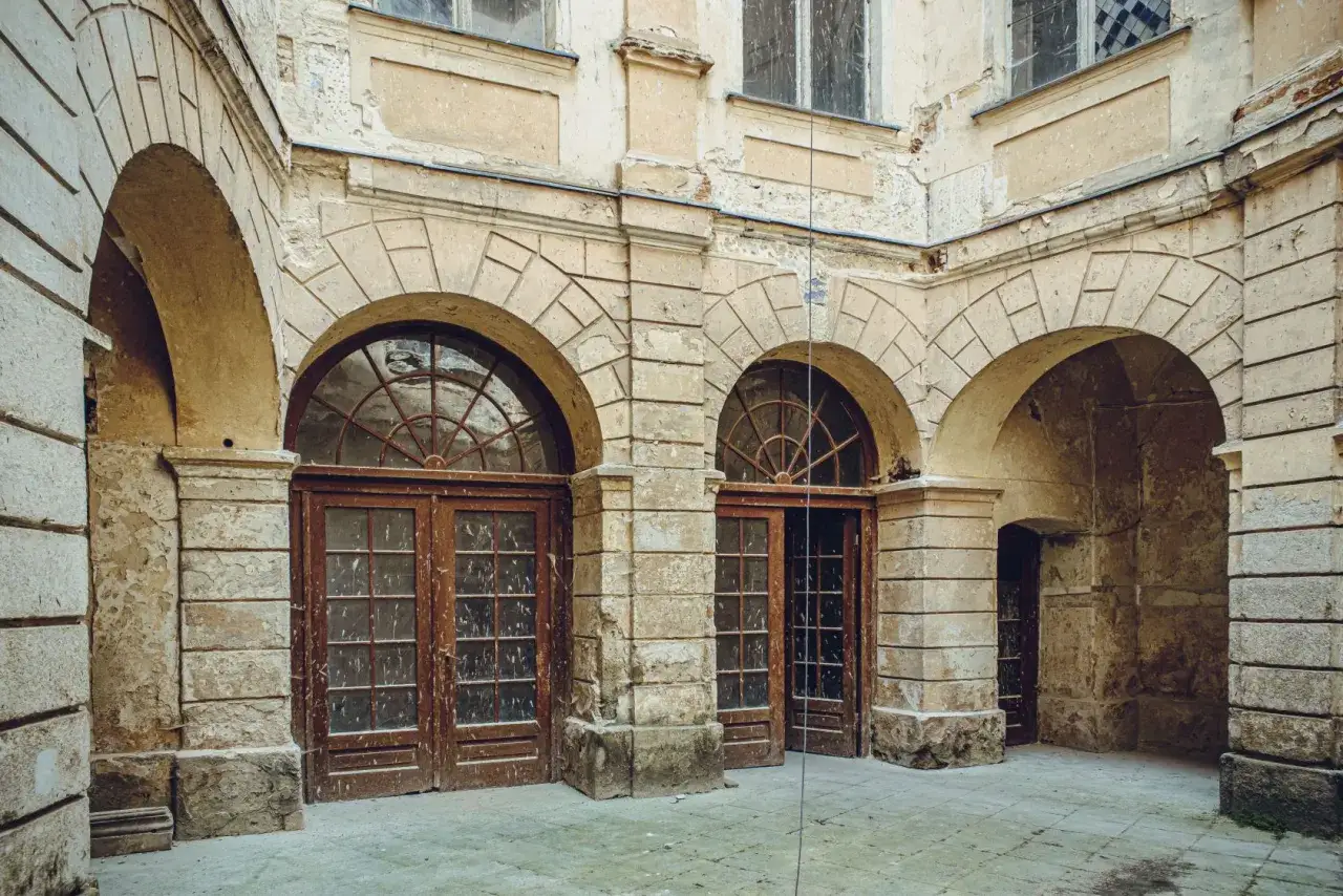 Zniszczone, zabytkowe arkady i drewniane drzwi pałacu Domanice, świadkowie minionej epoki.