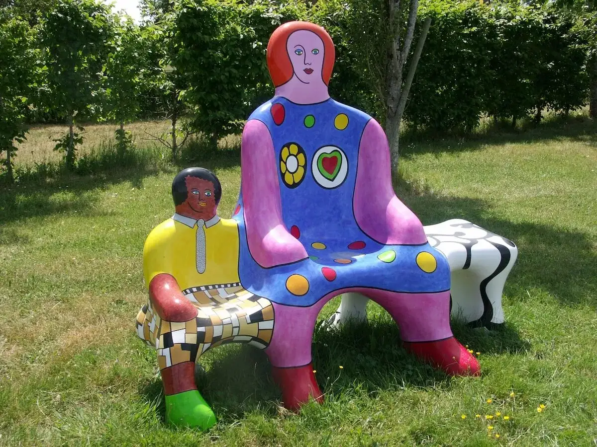 Deux sculptures color&eacute;es de Niki de Saint Phalle, un homme et une femme, s'assoient sur l'herbe.