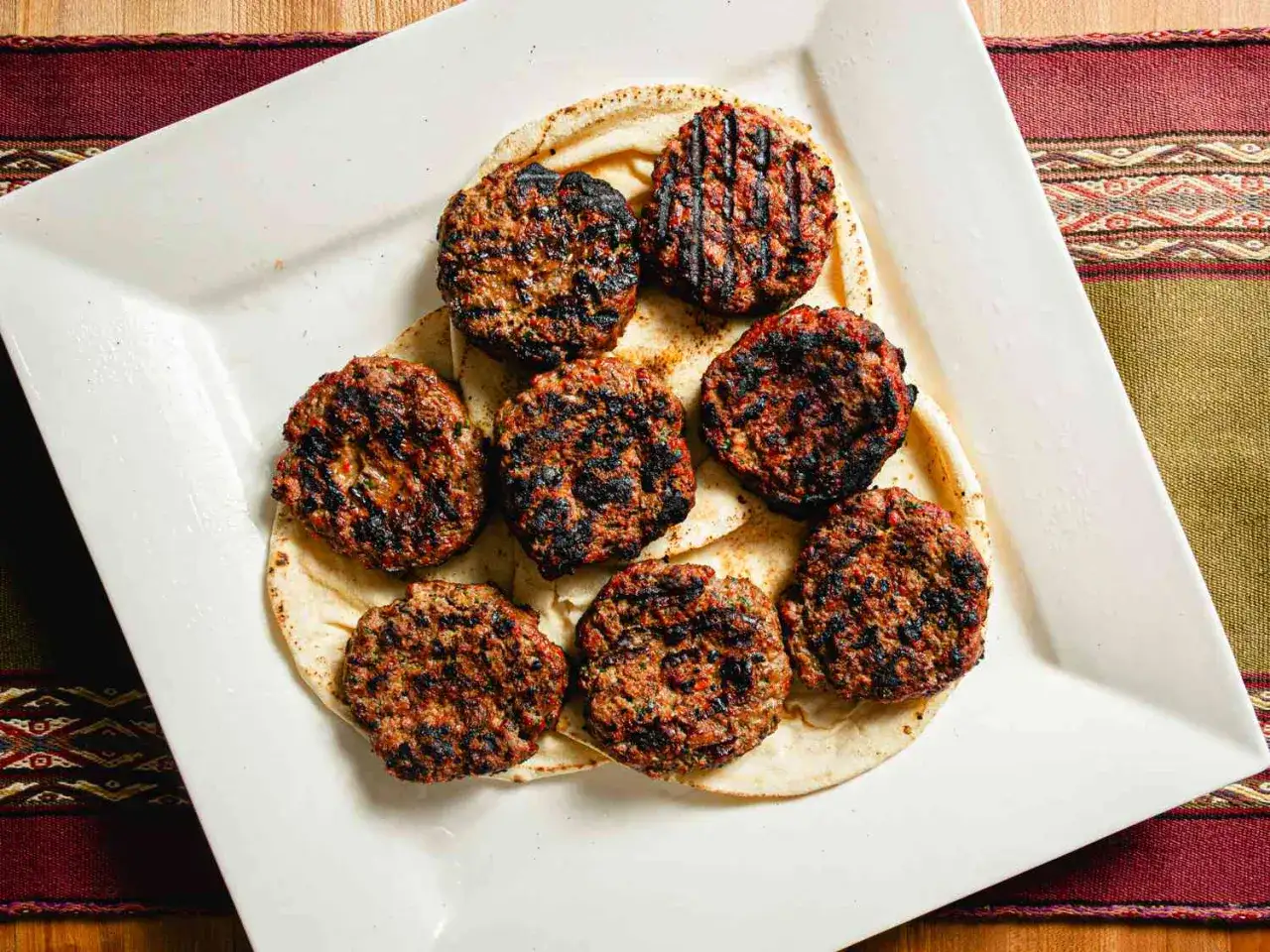 Gegrillte Hackfleisch-Patties auf Fladenbrot, perfekt für Ihre Hackfleisch Grill Rezepte.